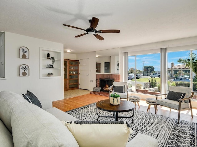 living room featuring wood-type flooring, ceiling fan, and a fireplace