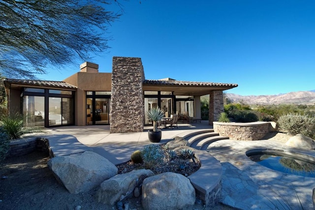 rear view of property with a mountain view and a patio area