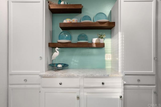 bar with light stone countertops and white cabinets