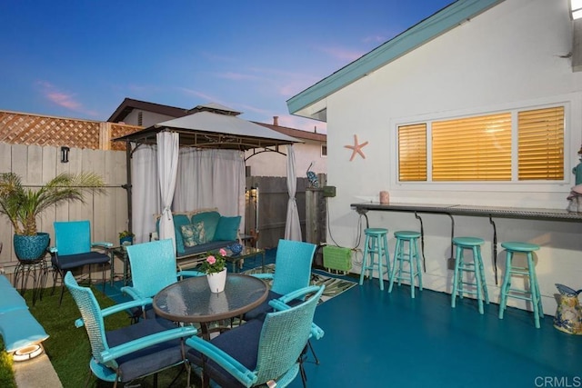 patio terrace at dusk featuring a bar and a gazebo