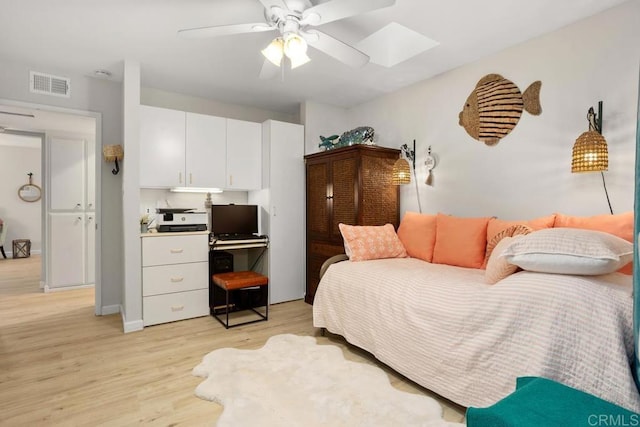 bedroom with ceiling fan, light hardwood / wood-style floors, and a skylight