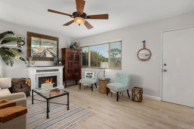 living area featuring light hardwood / wood-style flooring, a premium fireplace, and ceiling fan