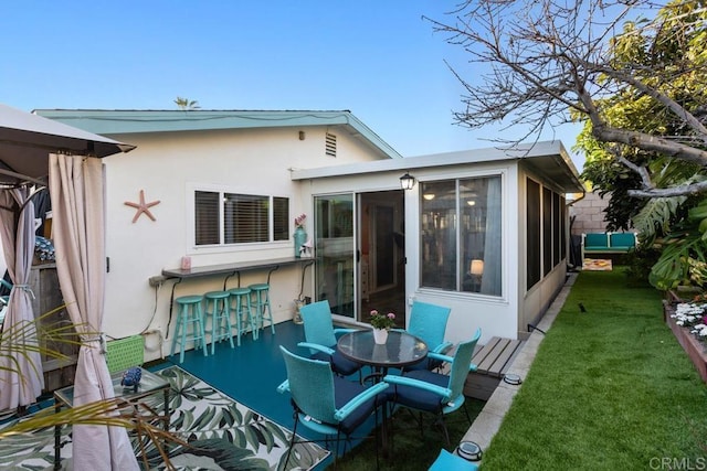 rear view of property featuring a yard, an outdoor bar, and a sunroom