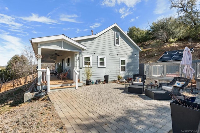 back of house with solar panels, ceiling fan, an outdoor hangout area, a deck, and a patio