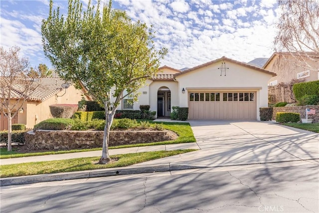 mediterranean / spanish-style home featuring driveway, an attached garage, a tiled roof, and stucco siding