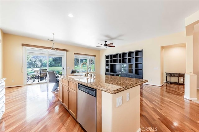 9431 Hughes Dr, Corona, CA 92883 - kitchen with light stone counters, a center island with sink, stainless steel dishwasher, a sink, and light wood-type flooring