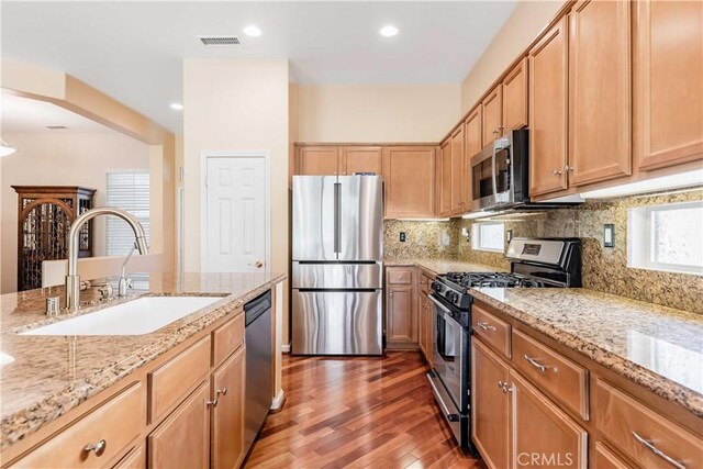 9431 Hughes Dr, Corona, CA 92883 - kitchen with light stone counters, stainless steel appliances, a sink, visible vents, and backsplash