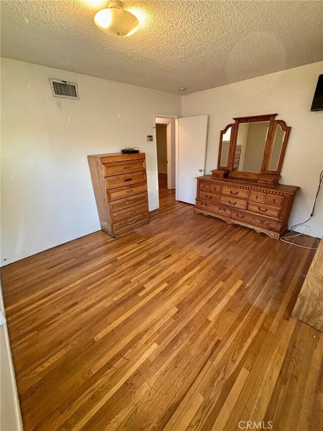 unfurnished bedroom featuring wood-type flooring and a textured ceiling