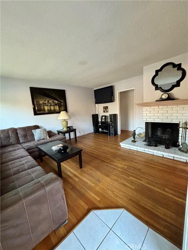 living room with hardwood / wood-style flooring, a brick fireplace, and a textured ceiling