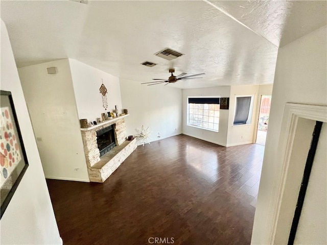 unfurnished living room featuring dark wood-type flooring, a fireplace, a textured ceiling, and ceiling fan