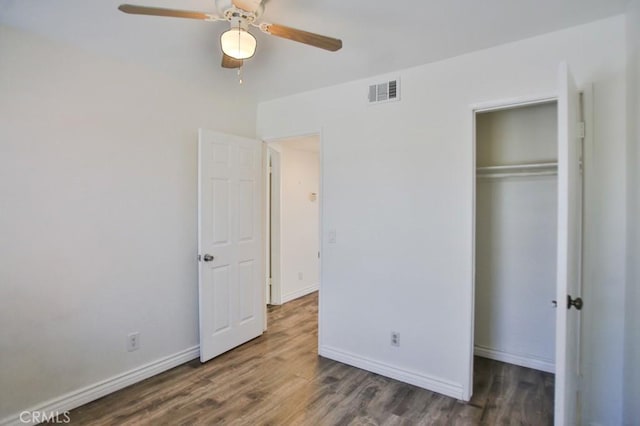 unfurnished bedroom with dark hardwood / wood-style flooring, a closet, and ceiling fan