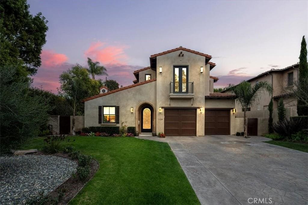 mediterranean / spanish-style home with a garage and a lawn