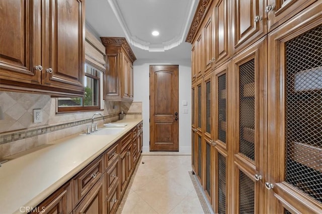 kitchen featuring light tile patterned floors, a tray ceiling, sink, and backsplash