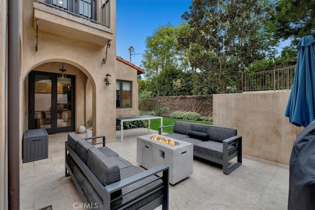 view of patio with french doors, a balcony, and an outdoor living space with a fire pit