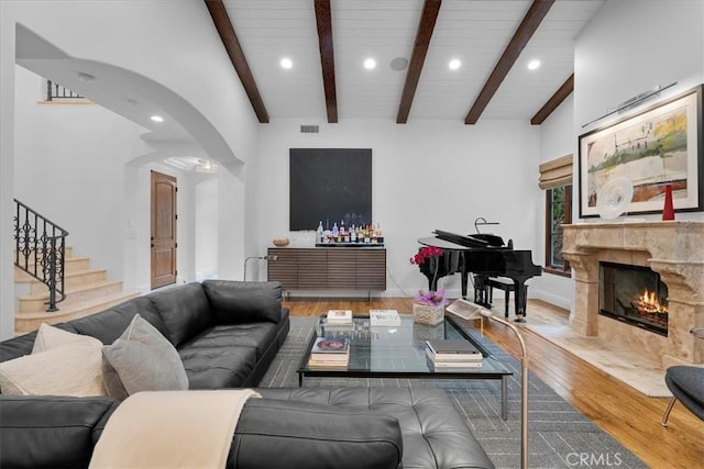 living room featuring hardwood / wood-style floors, beam ceiling, and a tile fireplace