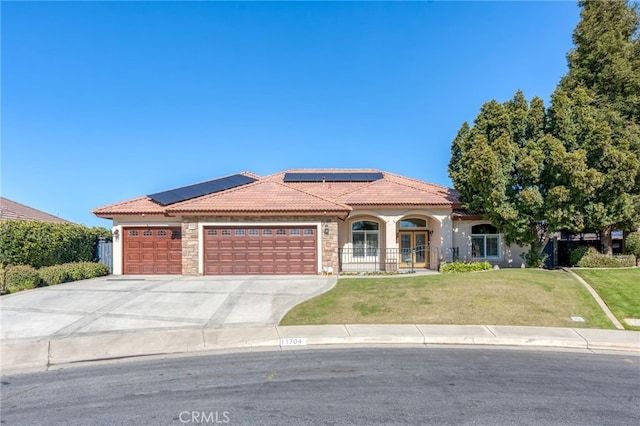 view of front of property featuring a garage, a front lawn, and solar panels