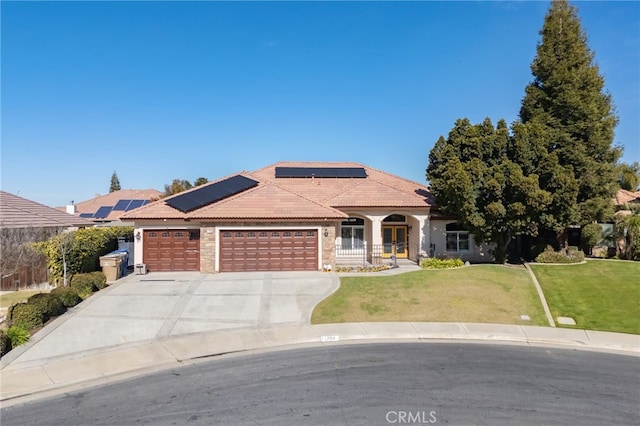 view of front of home with a garage, a front yard, and solar panels