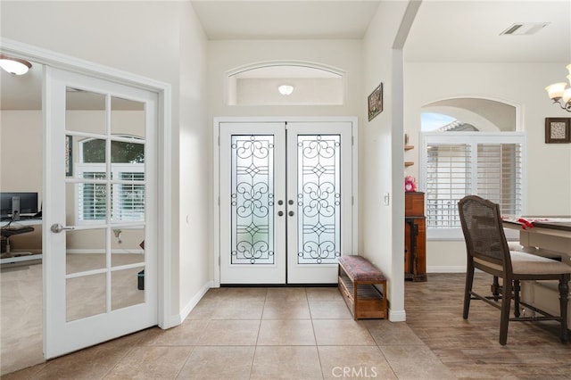 entryway featuring french doors, a chandelier, light tile patterned floors, and a wealth of natural light