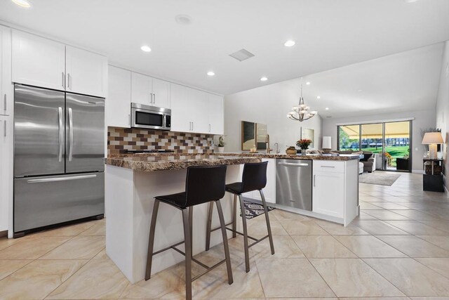 kitchen featuring a breakfast bar, appliances with stainless steel finishes, white cabinetry, decorative backsplash, and kitchen peninsula