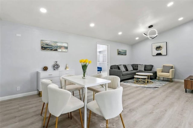 dining space featuring vaulted ceiling and light wood-type flooring