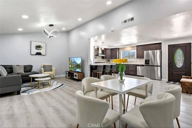 living room featuring lofted ceiling and light hardwood / wood-style floors