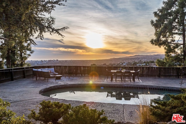 pool at dusk featuring a mountain view, an outdoor hangout area, and a patio area