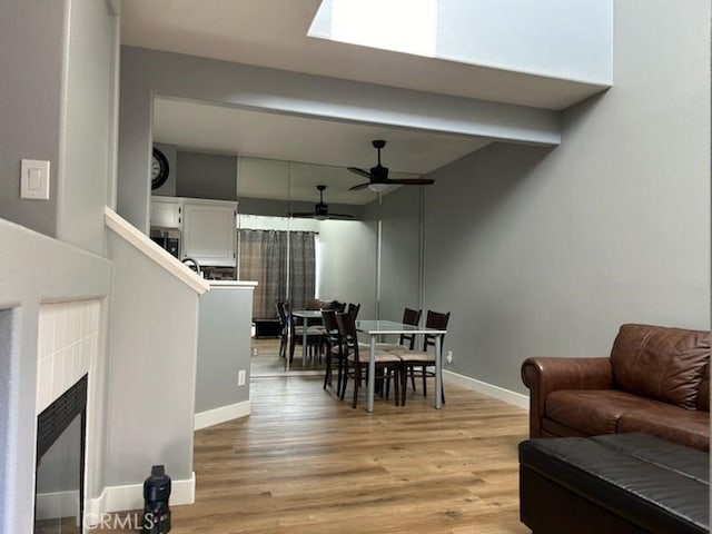 living room with beamed ceiling, ceiling fan, and light hardwood / wood-style flooring