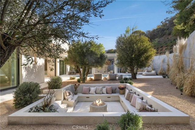 view of home's community with a patio and an outdoor living space with a fire pit