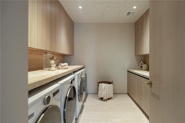 clothes washing area featuring separate washer and dryer, cabinets, and light wood-type flooring