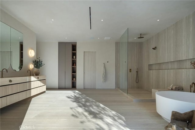 bathroom with wood finished floors, a freestanding tub, vanity, and a walk in shower