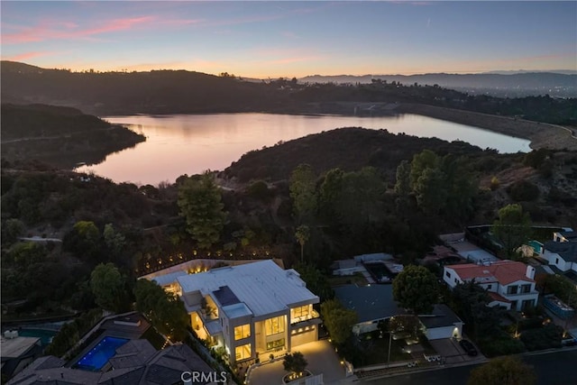 aerial view at dusk featuring a water view