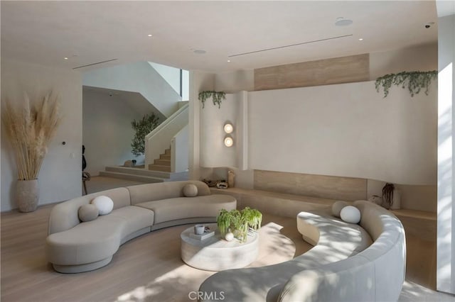 sunken living room featuring light wood-style flooring and stairs