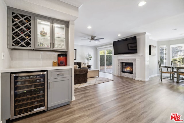 bar with crown molding, gray cabinetry, tasteful backsplash, wood-type flooring, and beverage cooler