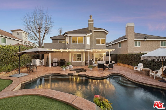 back house at dusk featuring a pergola, a pool with hot tub, and a patio area