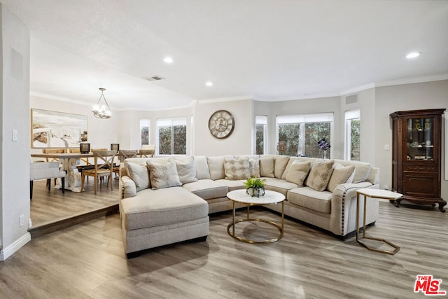 living room featuring a notable chandelier, wood-type flooring, and ornamental molding