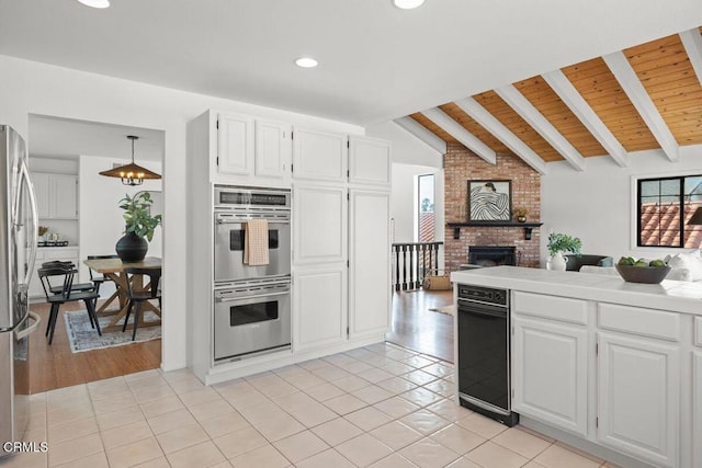 kitchen with lofted ceiling with beams, hanging light fixtures, stainless steel appliances, a fireplace, and white cabinets