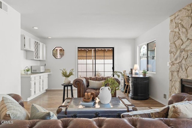 living room with a fireplace and light wood-type flooring