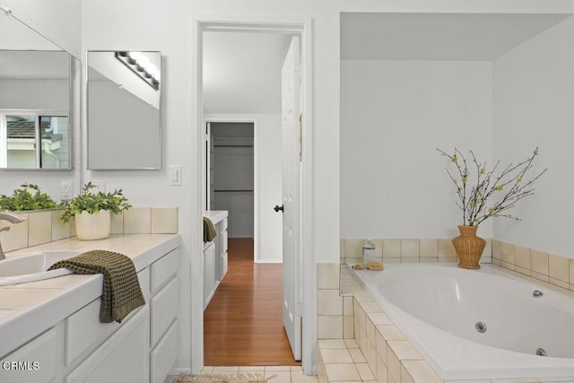 bathroom featuring a relaxing tiled tub, vanity, and hardwood / wood-style floors