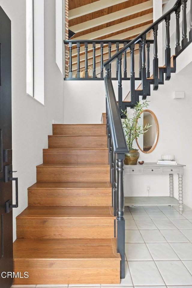 stairs featuring beamed ceiling, tile patterned flooring, and wooden ceiling