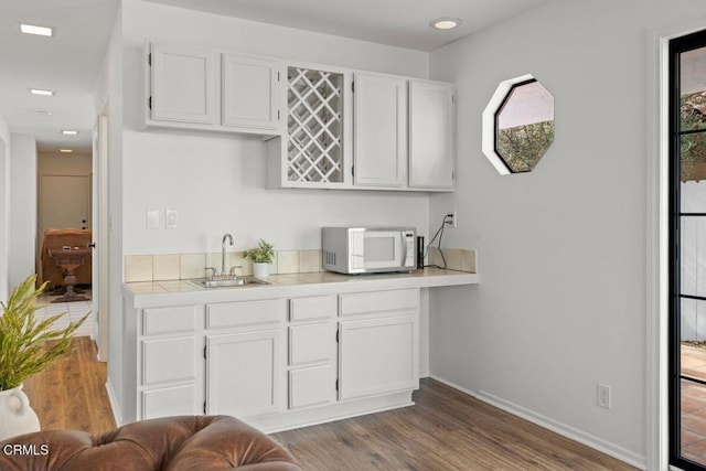 bar with dark wood-type flooring, sink, and white cabinets