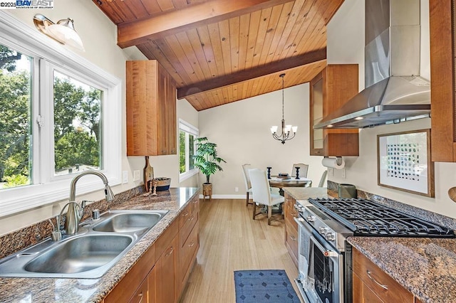 kitchen featuring decorative light fixtures, sink, dark stone countertops, stainless steel range, and wall chimney range hood