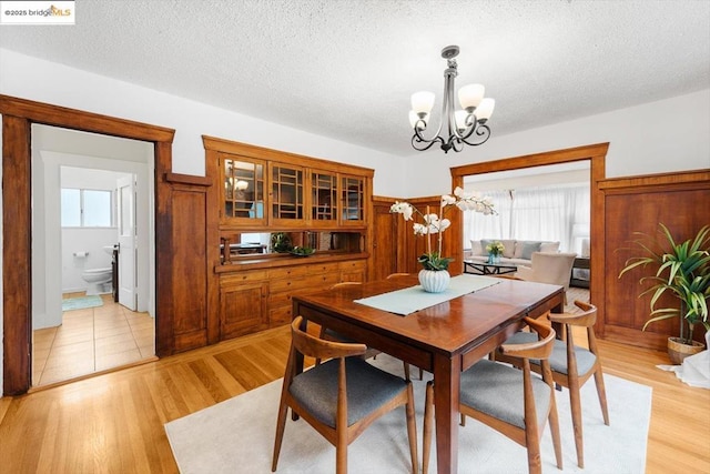 dining area featuring a chandelier, a textured ceiling, and light wood-type flooring