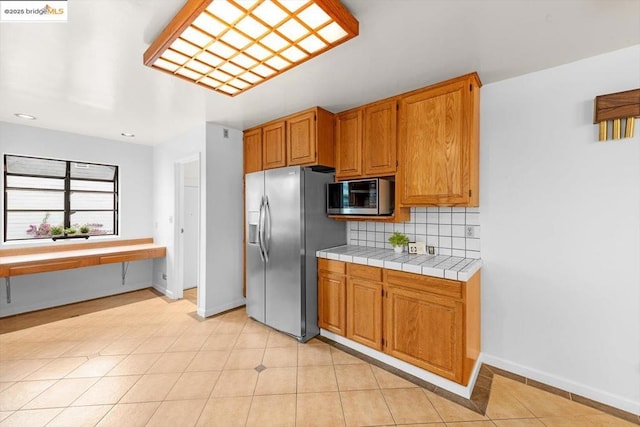 kitchen featuring stainless steel appliances, tasteful backsplash, tile countertops, and light tile patterned floors