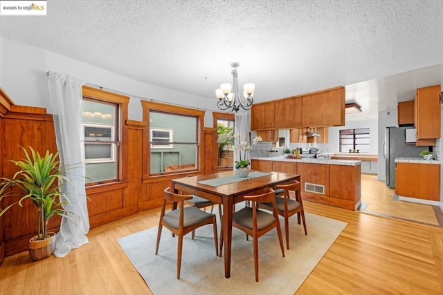 dining area featuring a textured ceiling, a notable chandelier, and light hardwood / wood-style floors