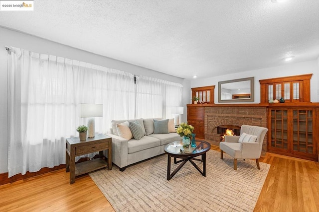 living room with a fireplace, light hardwood / wood-style floors, and a textured ceiling