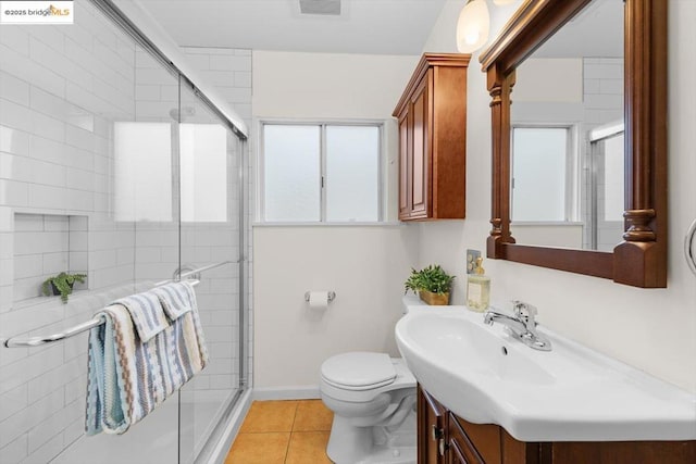 bathroom featuring toilet, vanity, a shower with door, and tile patterned flooring