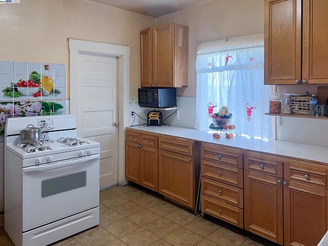 kitchen featuring white gas range and decorative backsplash