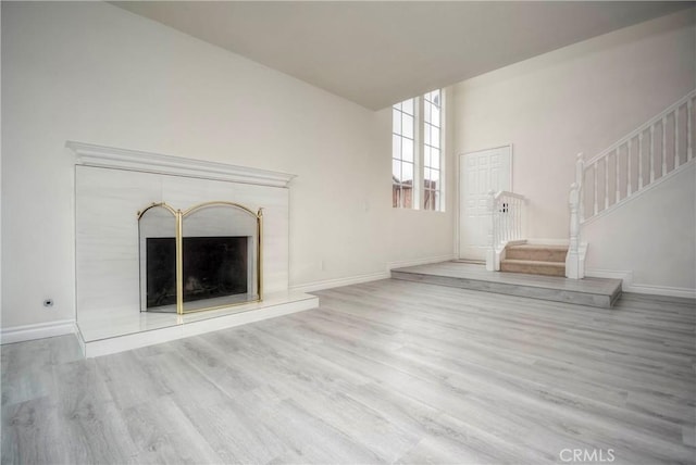 unfurnished living room featuring a towering ceiling and light hardwood / wood-style floors