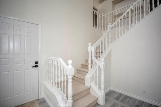 staircase featuring a high ceiling and wood-type flooring