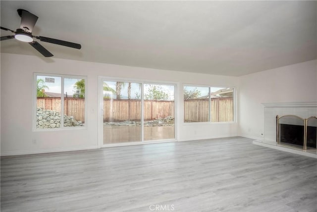 unfurnished living room featuring ceiling fan, a wealth of natural light, and light wood-type flooring